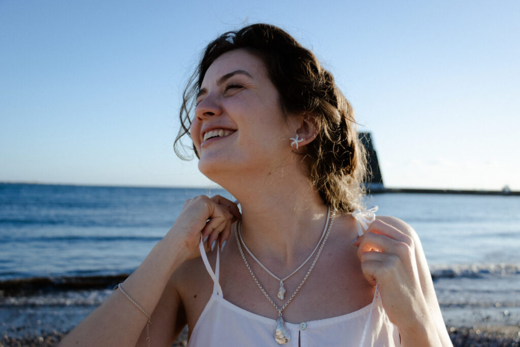 Modelo com pendente buzio, pendente mexilhão e brincos estrela do mar da coleção mar de prata com fios em prata.